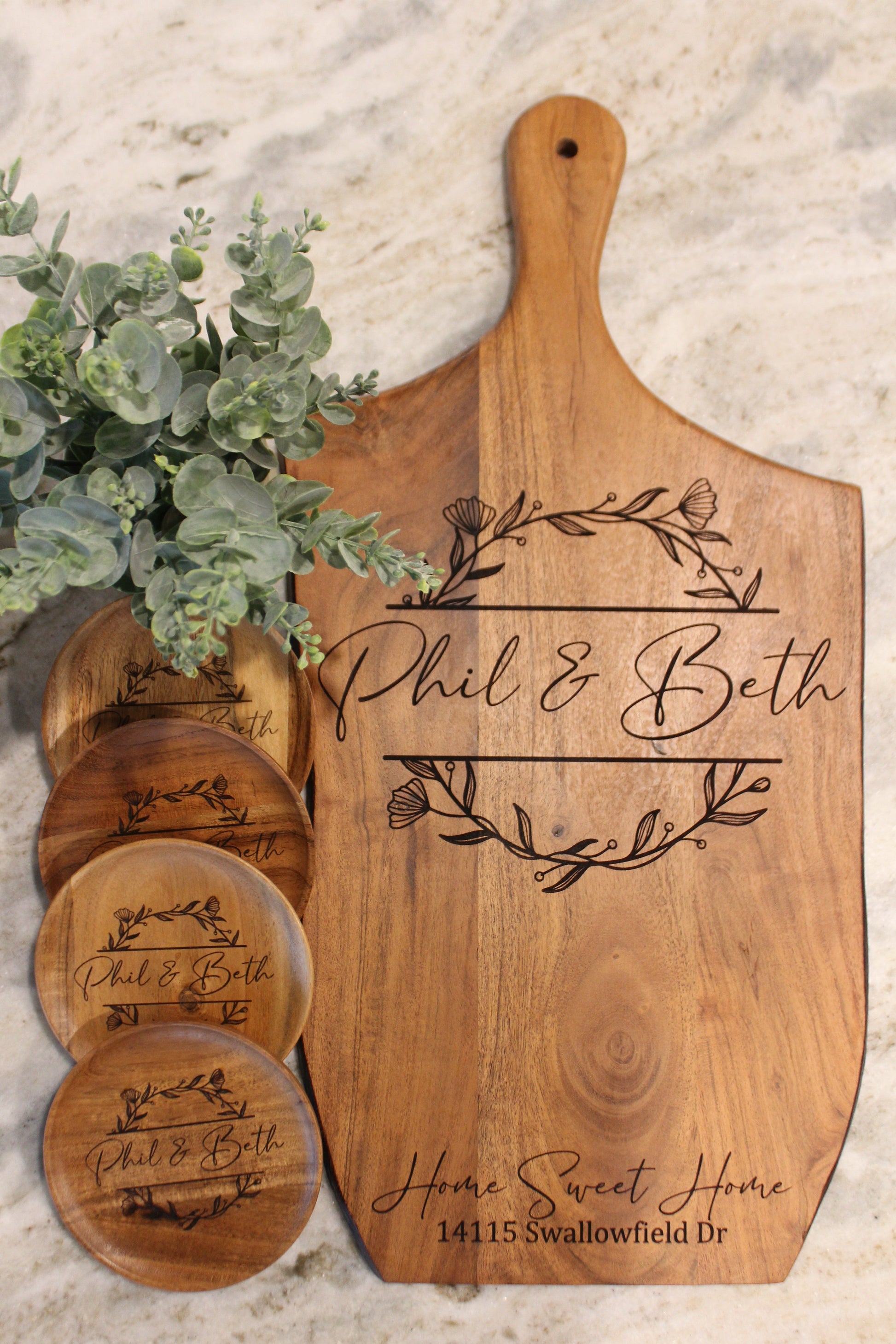 Wooden cutting board and coasters with engraved text on a marble surface